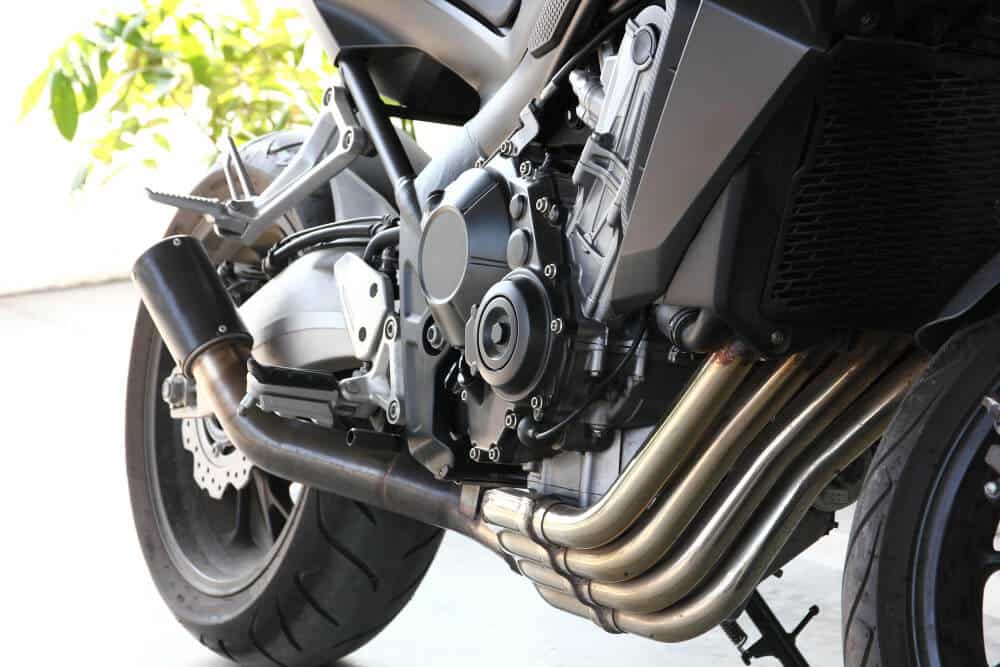 Pot d'échappement d'une moto avec une petite explosion de flamme (pétarade) lors d'une tentative de démarrage.