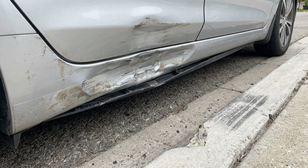 Bas de caisse de voiture enfoncé et frotté suite à un passage sur un trottoir haut.