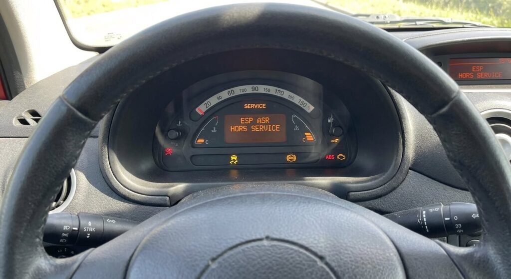 Tableau de bord de voiture affichant le message d'alerte ESP ASR hors service avec le voyant de glissade allumé.