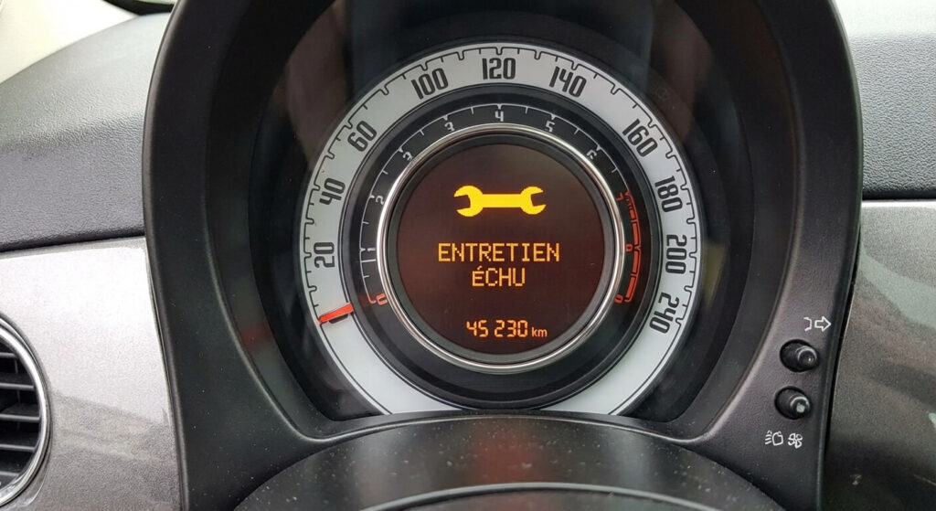 Tableau de bord de Fiat 500 affichant un message de maintenance ou une icône de clé à molette indiquant que le coupon est échu.