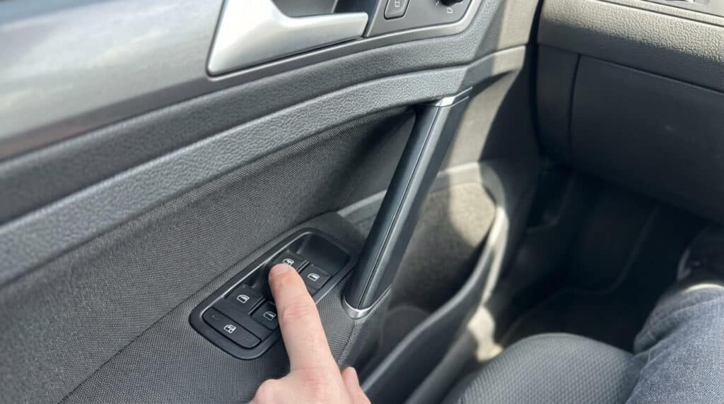 Vitre électrique Volkswagen ne remonte plus automatiquement : La solution 2 Commande de lève-vitre sur une portière de Volkswagen Golf, doigt maintenant le bouton levé pour la réinitialisation