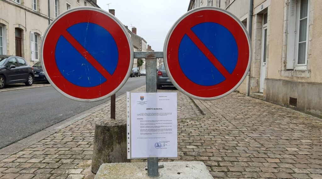 Panneaux officiels d'interdiction de stationner posés sur un trottoir avec l'arrêté municipal affiché sous plastique
