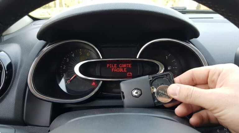 Tableau de bord Renault Clio 4 affichant "Pile carte faible" et main tenant une carte de démarrage ouverte avec une pile CR2032 neuve