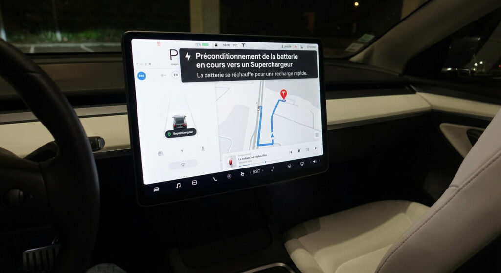 Écran central d'une Tesla Model 3 affichant le message de préconditionnement de la batterie en cours vers un Superchargeur