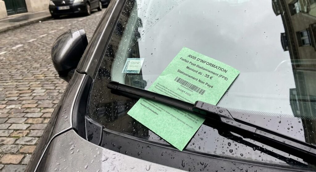 Le petit papier vert de l'Avis d'Information glissé sous l'essuie-glace d'une voiture, signalant l'établissement d'un Forfait Post-Stationnement