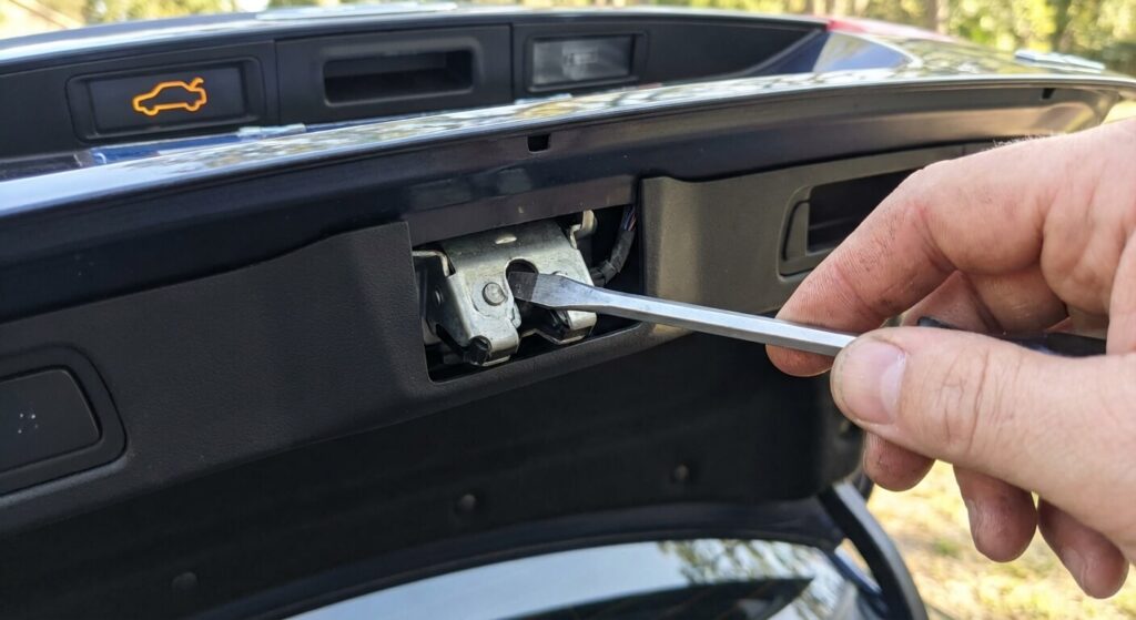 Utilisation d'un tournevis pour fermer manuellement le loquet de la serrure du hayon de coffre afin de tromper le capteur électronique