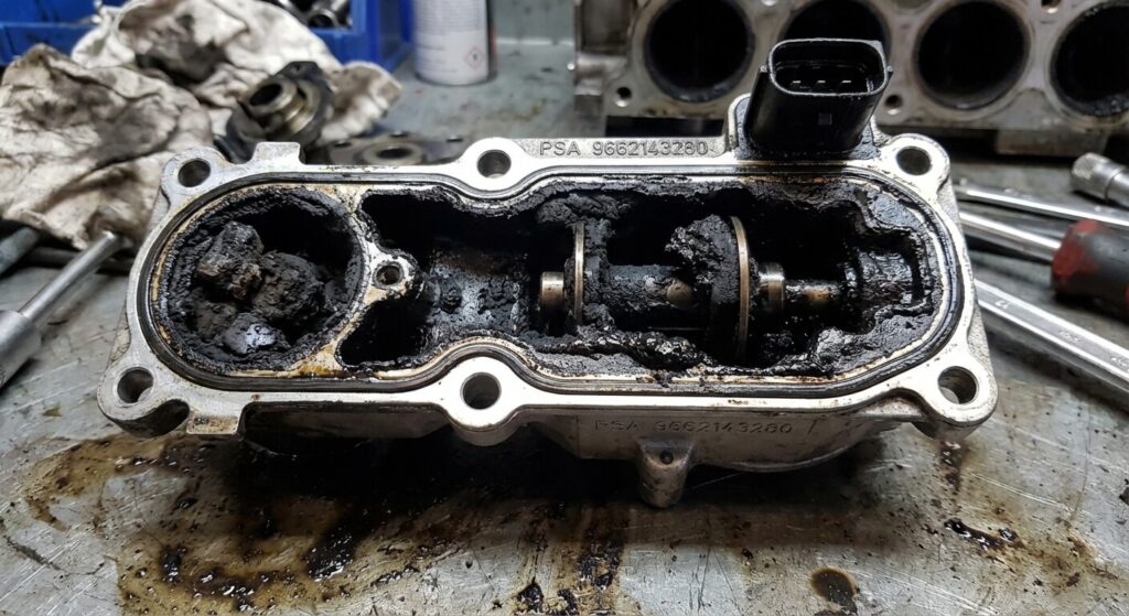Supprimer la vanne EGR sur 1.6 HDI 90 : Risques et solutions 2 Vanne EGR d'un moteur PSA 1.6 HDi totalement obstruée par de la calamine noire et grasse