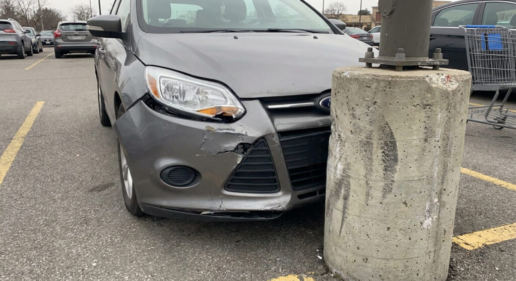 Pare-chocs avant froissé d'un véhicule ayant percuté un poteau de stationnement en béton