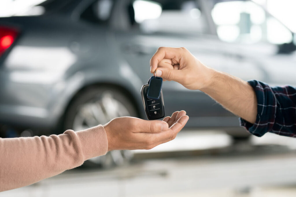 Gros plan sur la remise des clés d'une voiture neuve symbolisant le choix réussi entre concession et mandataire.