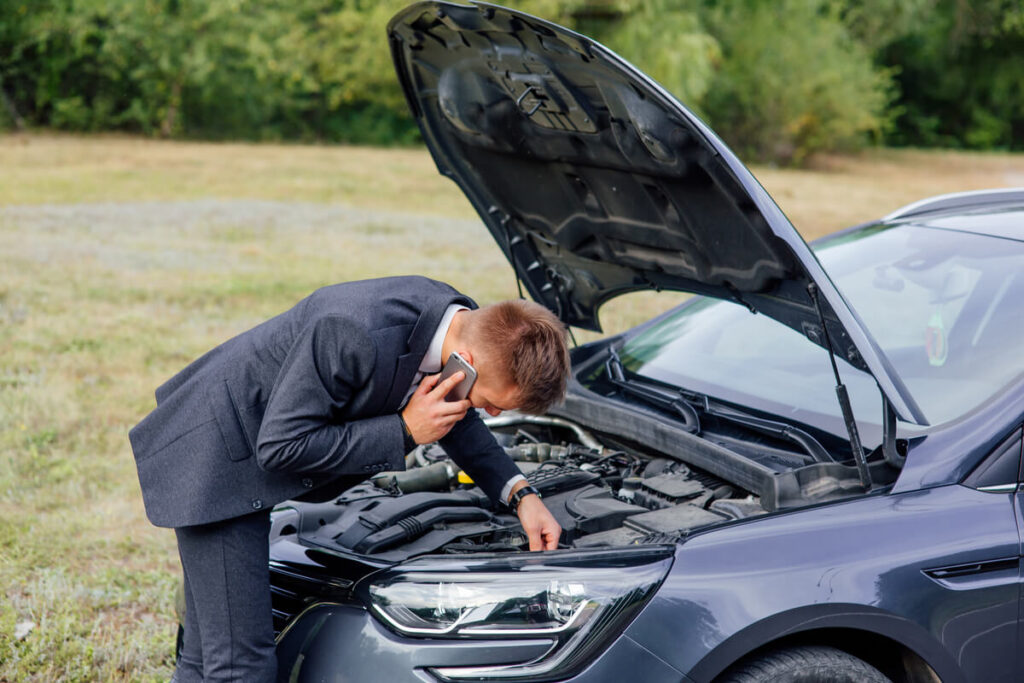 Acheteur inspectant le moteur d'une voiture d'occasion récemment achetée tombée en panne