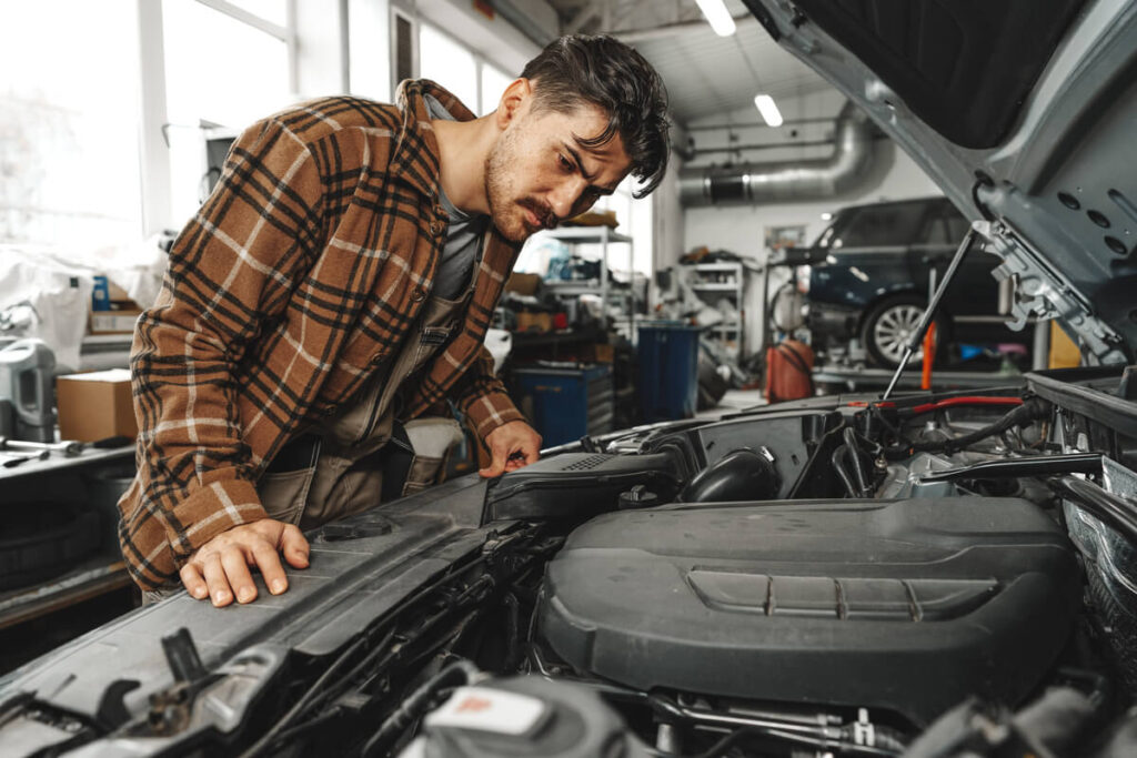 Inspection visuelle du bloc moteur d'une voiture d'occasion pour vérifier l'absence de fuites d'huile avant l'achat.
