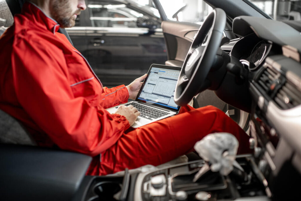 Voyant moteur allumé : ça passe au contrôle technique ? 3 Un technicien branchant la prise diagnostic d'une voiture lors du contrôle technique.