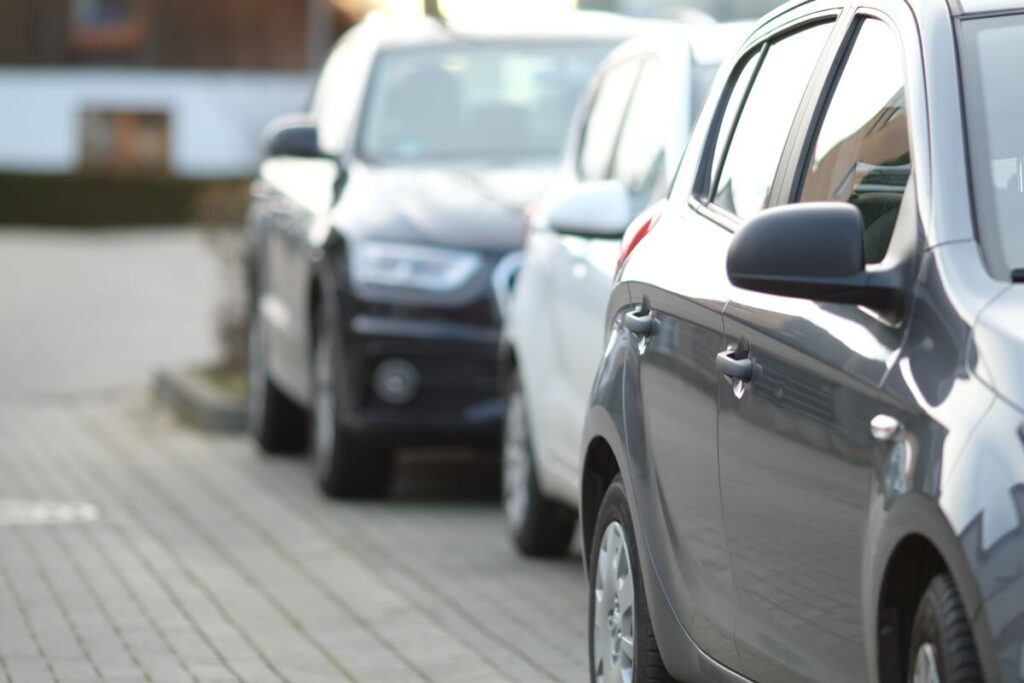 Un alignement de voitures de fonction blanches et d'utilitaires neufs sur le parking d'une entreprise pour ses salariés.