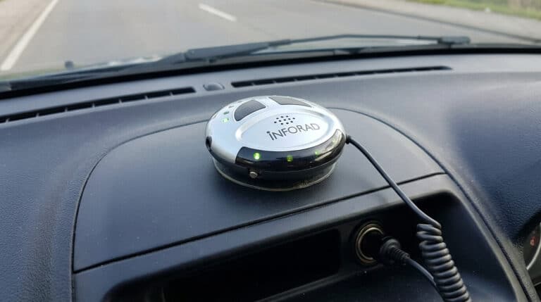 Accueil 8 Un ancien boîtier avertisseur de radars Inforad de forme ronde fixé sur le tableau de bord d'une voiture.