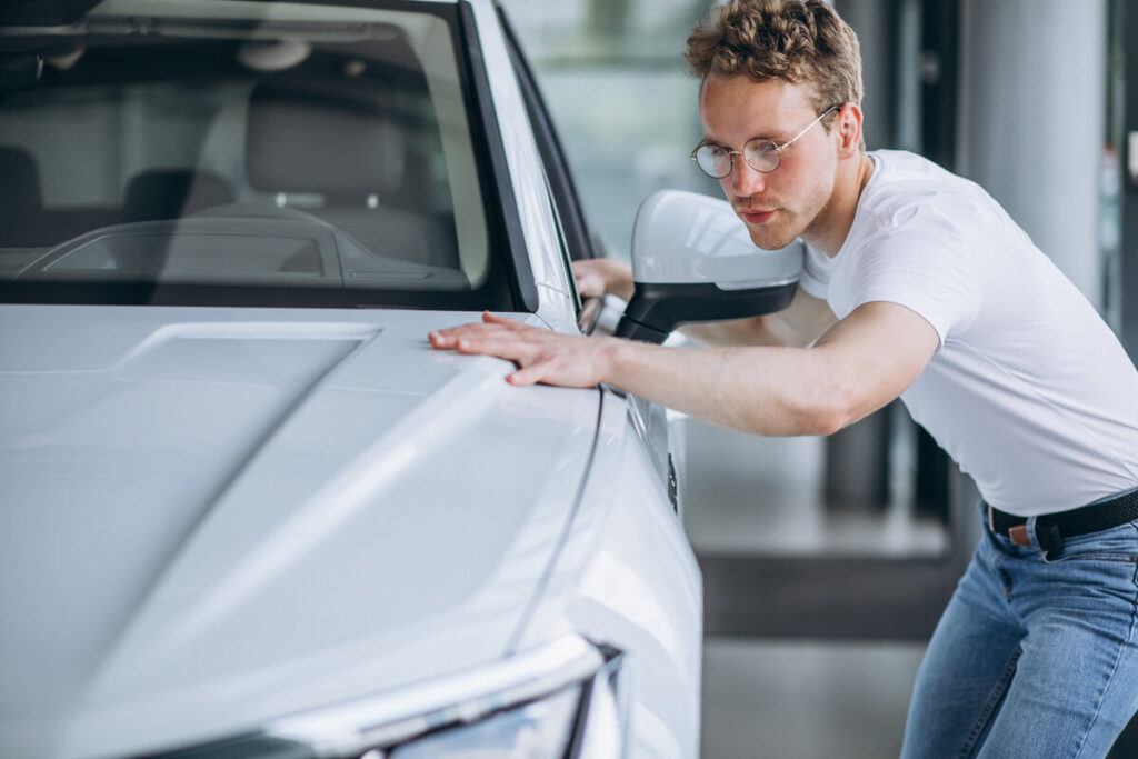 Un automobiliste prenant en photo une rayure sur la portière de sa voiture pour obtenir un devis de carrosserie en ligne.