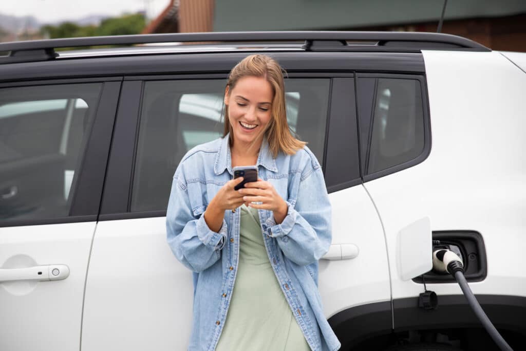 Une conductrice consultant l'application de navigation de son véhicule pour repérer les bornes de recharge sur son trajet.