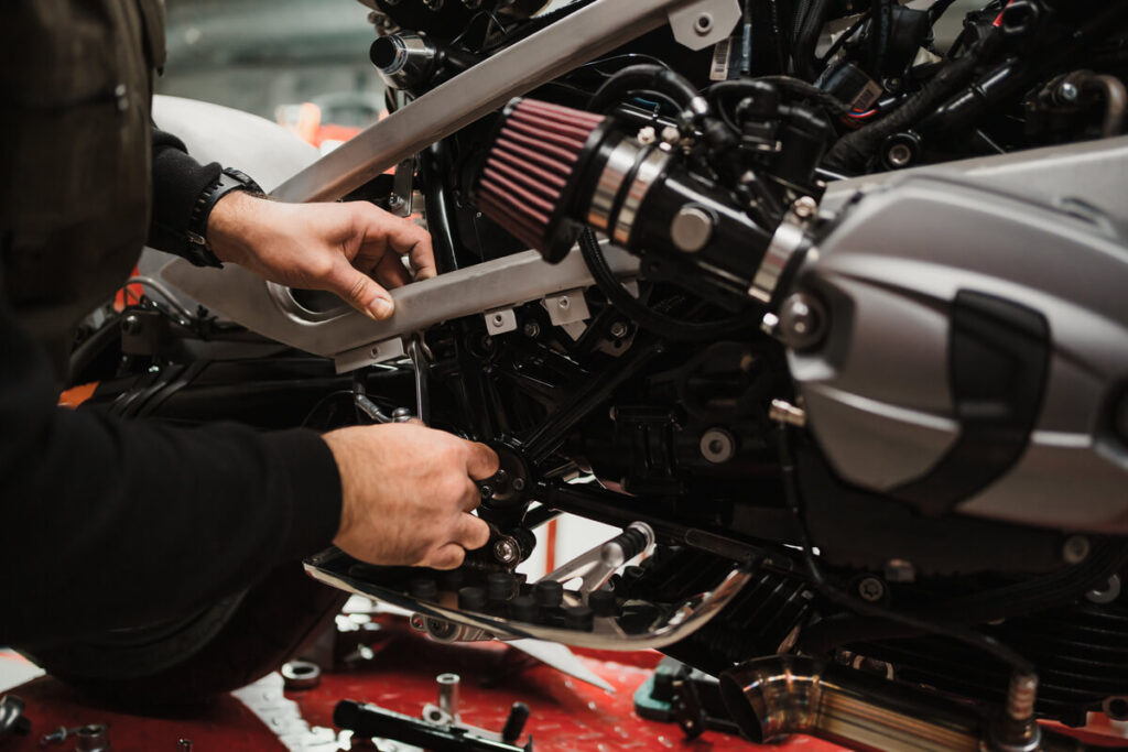 Panne ou casse mécanique : l'assurance moto couvre-t-elle ? 3 Un mécanicien professionnel travaillant sur le moteur et les pièces mécaniques d'une moto de grosse cylindrée.