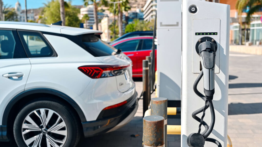 Un SUV électrique moderne branché sur une borne de recharge rapide sur l'autoroute.
