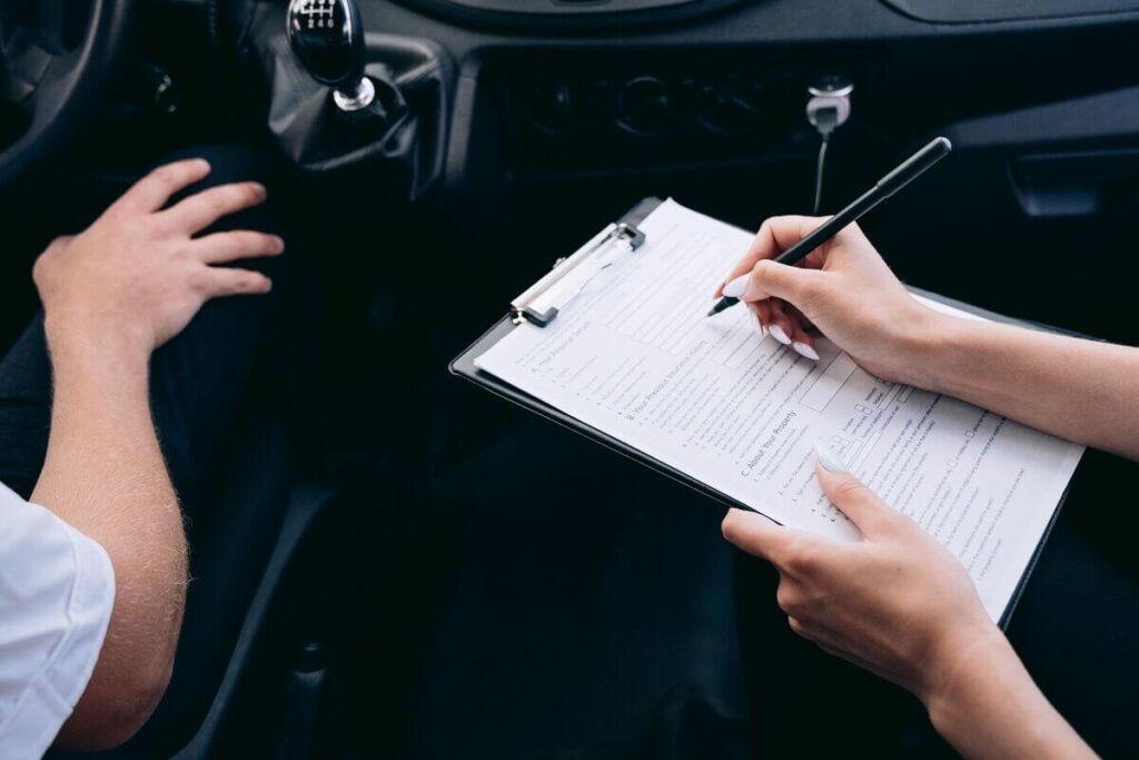 Voiture incendiée : quelles démarches pour l'assurance et l'enlèvement de l'épave ? 4 Un automobiliste complétant sa déclaration de sinistre incendie pour son assurance auto.