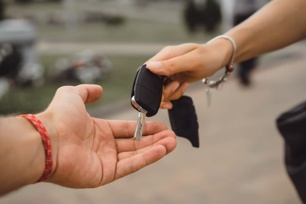 Automobiliste remettant les clés de son ancienne voiture avant de prendre possession de la nouvelle.