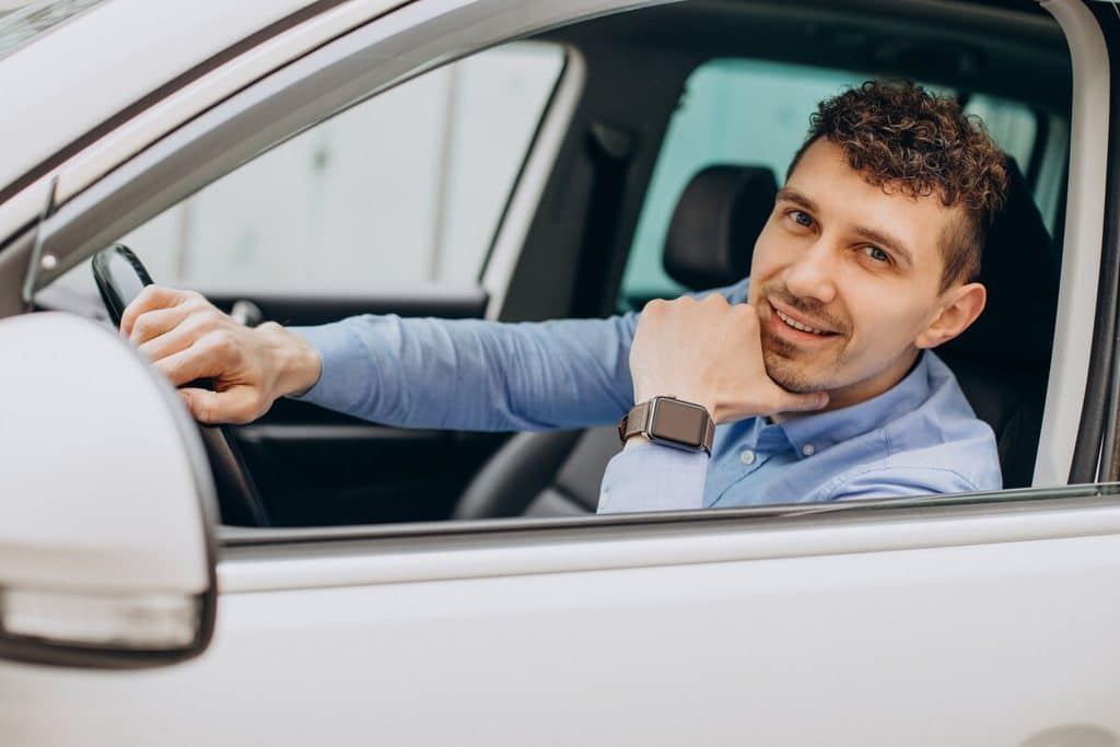 Quelle assurance auto correspond vraiment à votre situation ? 4 Conducteur souriant au volant de son véhicule sur la route.
