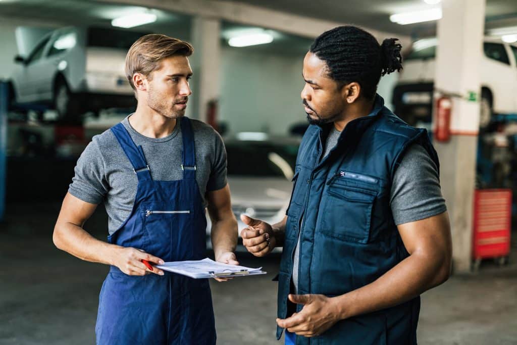 Client et responsable d'atelier examinant un ordre de réparation automobile après un litige.
