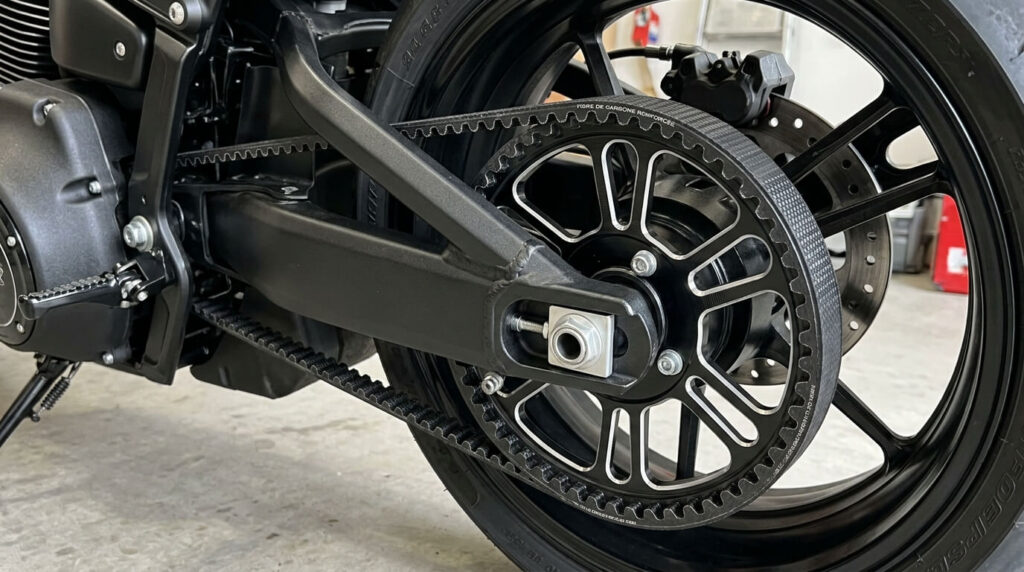 Moto à transmission par courroie : avantages, inconvénients et modèles 1 Courroie crantée renforcée en fibre de carbone entraînant la poulie arrière d'une moto.
