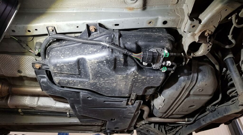 Réservoir et faisceau électrique de la pompe d'additif FAP sous le châssis d'une Peugeot.